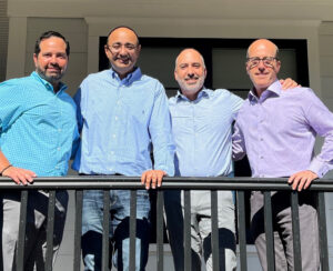 Sanjit Singh poses with four other men in collared shirts on balcony.